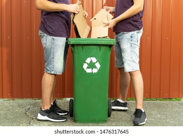 Men Putting Cardboard Into Recycle Bin 