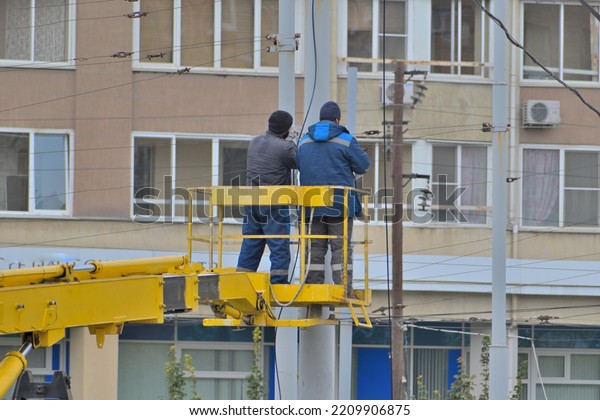 Men\
repair the contact tram network on an autumn\
day