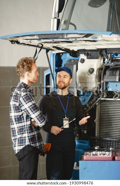Men repair a truck. Man teaches repair a car. Two
men in uniform