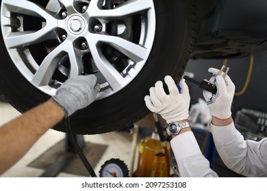 Men repairmen fixing car on lift in workshop closeup - Powered by Shutterstock