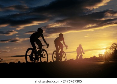 The men ride bikes at sunset with orange-blue sky background. Abstract Silhouette background concept. - Powered by Shutterstock