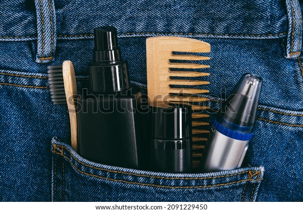 Men self care beauty kit, male beauty\
care cosmetic products and devices in blue jeans denim pocket. Man\
self care set with skin and hair care\
products.