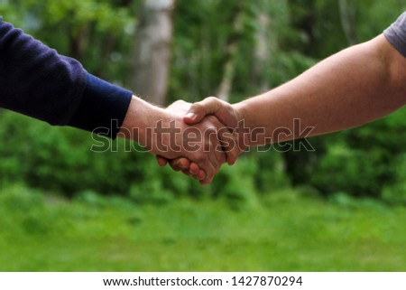 Men shake hands. Businessmen handshaking after good deal. Concept of successful business partnership meeting . Holding hands. Close Up view on green nature background. Minimal composition, copy space.