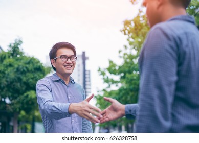 Men Shaking Hands. Sealing A Deal! Two Happy Young Asian Businessman Shaking Hands While  Standing On The Paving Tiles, Cement Brick Floor.