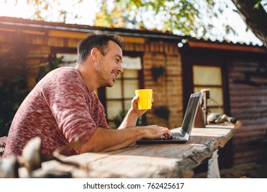 Men sitting in the at backyard patio drinking coffee and using laptop - Powered by Shutterstock