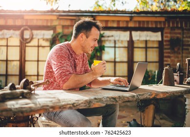 Men sitting in the at backyard patio drinking coffee and using laptop - Powered by Shutterstock