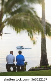 Men sitting under palm tree on beach