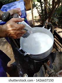 Men are squeezing raw materials into hot water to make noodles.