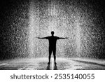 a men standing in heavy rain by opening there arms towards the sky 