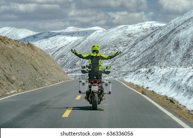 Men standing on motorbike while driving and free hands in snow moutain,Sichuan,China