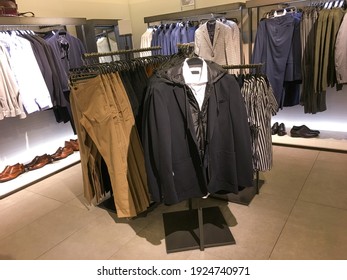 Men suits and T-shirt with pants on hanger. Men clothes hanging on wooden hangers in a store