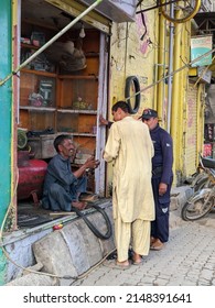 Men Talking In The Street. Tire Hanging On The Wall. Tire Shop Owner. Multan, Pakistan. 04. 10. 2022.