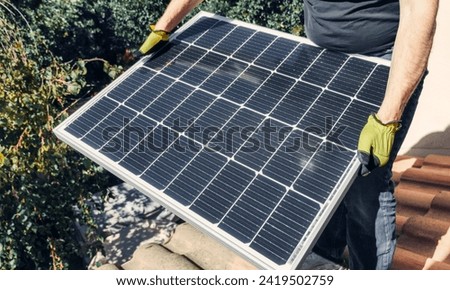 Men technicians carrying photovoltaic solar moduls on roof of house. installing solar panel system outdoors. Concept of alternative and renewable energy.