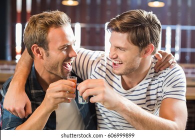 Men toasting with shots while looking at each other