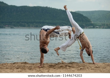 Men train capoeira on the beach - concept about people, lifestyle and sport. Training of two fighters