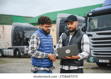 Men in vests shaking hands, finalizing a business deal in transportation logistics, with a truck fleet in the background