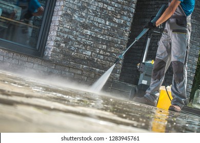 Men Washing Driveway Using Pressure Washer. Spring Time Cleaning.