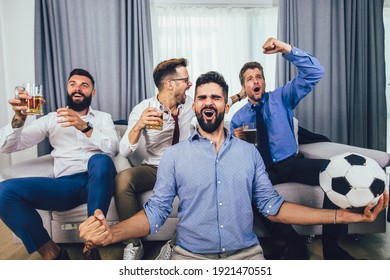 Men watching sport on tv together at home screaming cheerful. Group of friends sitting on the couch and watching a football game. - Shutterstock ID 1921470551