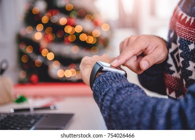 Men wearing blue sweater using smart watch during christmas