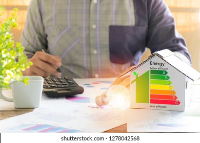 Men Who Are Calculating Cost Savings From Energy. Hand Holding A Pen. Detail Of House Efficiency Rating On Digital Tablet Screen. Concept Of Ecological And Bio Energetic House. Energy Class.