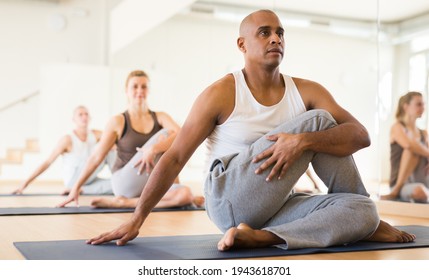 Men And Woman Exercising Yoga Poses In Fitness Center