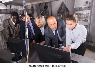Men and women in business suits solving quests to get out of escape room