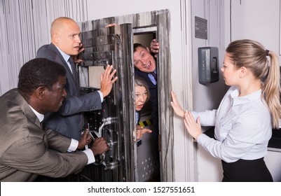 Men And Women In Business Suits Solving Puzzles To Get Out Of Horror Style Escape Room