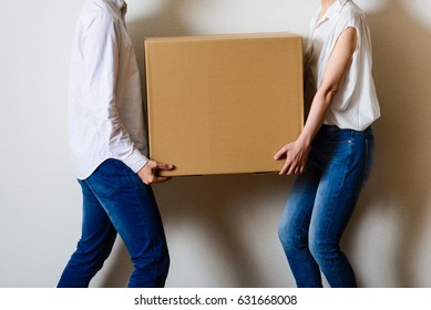 Men and women couple carrying a cardboard box