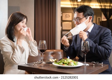 Men And Women Having A Mask Dinner At A Restaurant