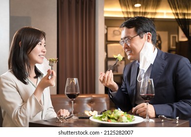 Men And Women Having A Mask Dinner At A Restaurant