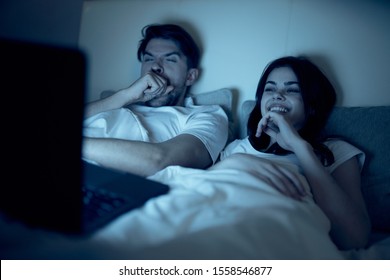 Men And Women Lie In Bed Laptop Watching Movie Night