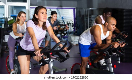 Men and women ride stationary bike in a fitness club