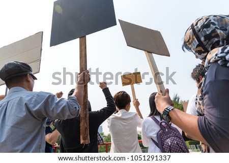 Men and women share a protest sign  hold a megaphone. Mob concept, The youth crowd gathered to protest.
