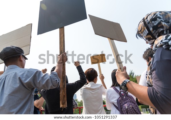 Men and women share a\
protest sign  hold a megaphone. Mob concept, The youth crowd\
gathered to protest.