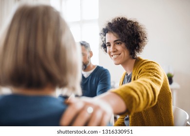 Men and women sitting in a circle during group therapy, supporting each other. - Shutterstock ID 1316330951