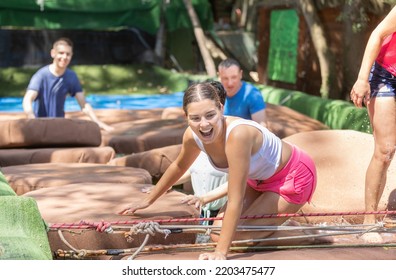 Men and women walking through water obstacle course in adventure park. Family on summer holiday. - Powered by Shutterstock