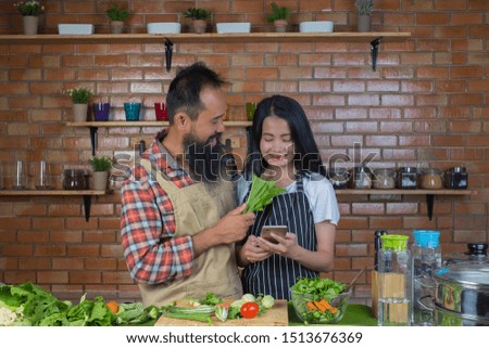 Men and women who tease each other while cooking in the kitchen with a red brick wall.
