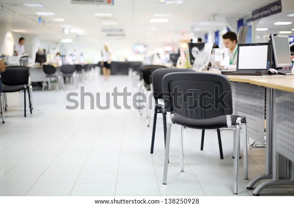 Men and women work at\
computers in car dealership office. Shallow depth of field. Focus\
on nearest chair.