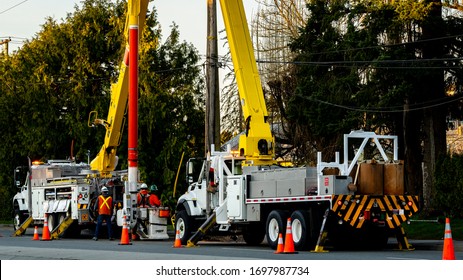 Men At Work On Electric Post Power Pole. Electrician Lineman Repairman Worker At Climbing. Crew, Construction.