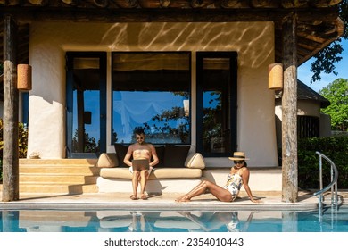 Men working at a laptop a digital nomad working at a swimming pool during a vacation on a tropical island. man and woman in the infinity pool during luxury vacation in a luxury pool villa