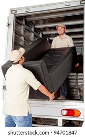 Men Working For A Moving Services Company Unloading A Sofa From A Truck