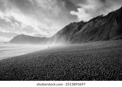 Menacing clay cliffs tower over the pebble beach below as the sea mist rolls in on a windy, cold winters day. - Powered by Shutterstock