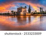 The Menara Pavilion and Gardens in Marrakesh, Morocco, captured at sunset with vibrant reflections on the serene lake, showcasing iconic Moroccan architecture.