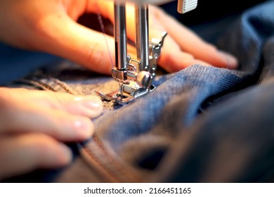 Mend jeans on a sewing machine. Patch torn jeans with a sewing machine. The concept of industrial production of handmade denim clothing. selective focus - Powered by Shutterstock