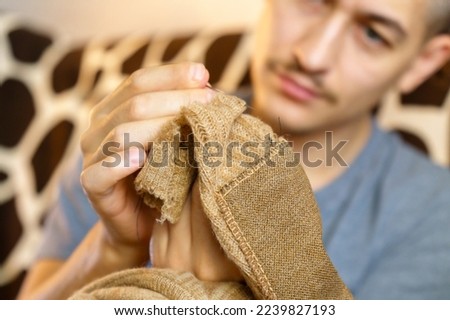 Mending clothes. A man is engaged in sewing. Household chores. Selective focus