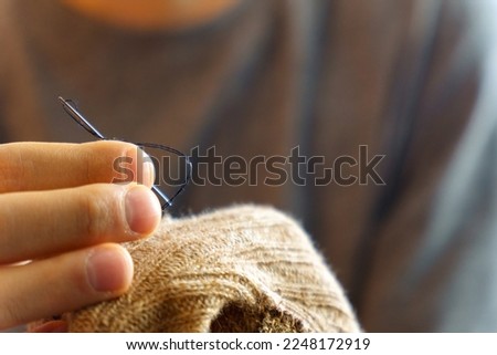 Mending clothes. Repairing woolen sweaters, shopping less concept. Selective focus