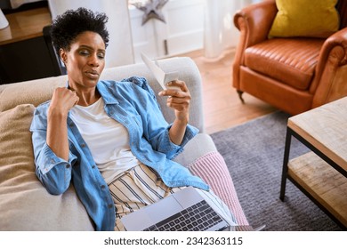 Menopausal Mature Woman At Home With Laptop Having Hot Flush Fanning Herself