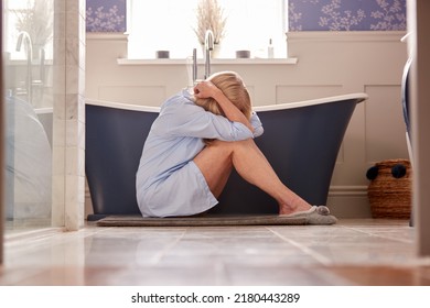 Menopausal Mature Woman Suffering With Incontinence Sitting On Bathroom Floor At Home