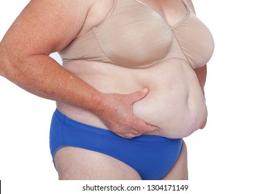 Menopausal woman with weight gain after brachioplasty, panniculectomy, abdominoplasty and mummy makeover. 45 degree view right hands holding excess abdominal weight, copy space. Makeover inspiration.