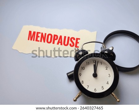 Menopause on Paper with Black Alarm Clock and Magnifying Glass – Women's Health Concept of Aging, Hormonal Changes, Time Awareness, and Medical Diagnosis. 